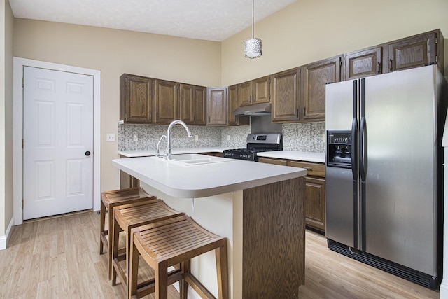 6001 Dover Ln, Michigan, MI 49684 - kitchen with stainless steel appliances, under cabinet range hood, tasteful backsplash, light countertops, and light wood finished floors