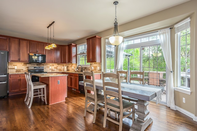 58799 Carriage Ln, South Lyon, MI 48178 - kitchen with appliances with stainless steel finishes, a kitchen island, decorative backsplash, and dark wood finished floors