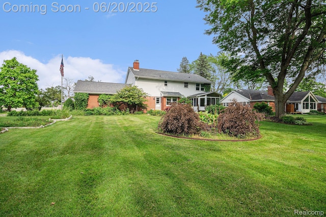 8276 Appleway Dr, Grand Blanc, MI 48439 - rear view of house with a chimney, a lawn, and brick siding