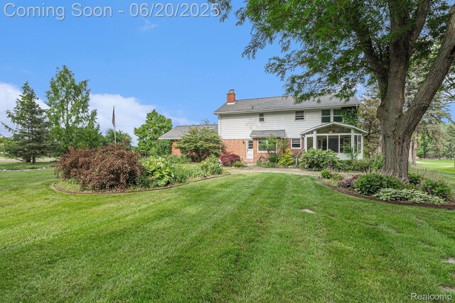 8276 Appleway Dr, Grand Blanc, MI 48439 - rear view of house with a chimney, a sunroom, a lawn, and brick siding