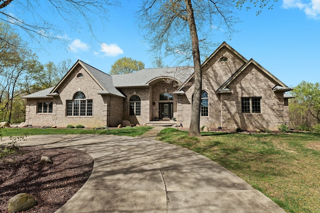 9997 Applegate Ln, Brighton, MI 48114 - french provincial home featuring brick siding, a front lawn, roof with shingles, and curved driveway