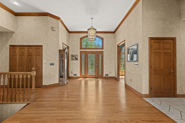 9997 Applegate Ln, Brighton, MI 48114 - foyer featuring light wood-style flooring, a towering ceiling, crown molding, a chandelier, and baseboards