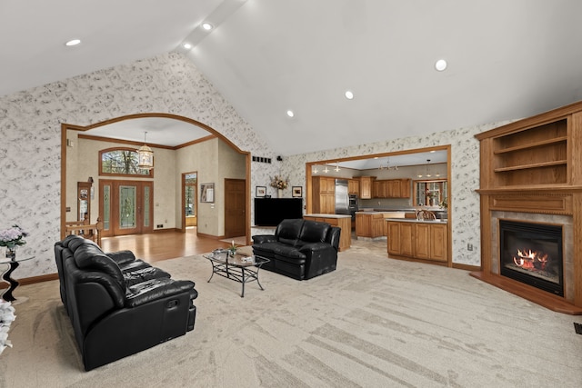 9997 Applegate Ln, Brighton, MI 48114 - living room featuring wallpapered walls, light carpet, baseboards, a glass covered fireplace, and high vaulted ceiling