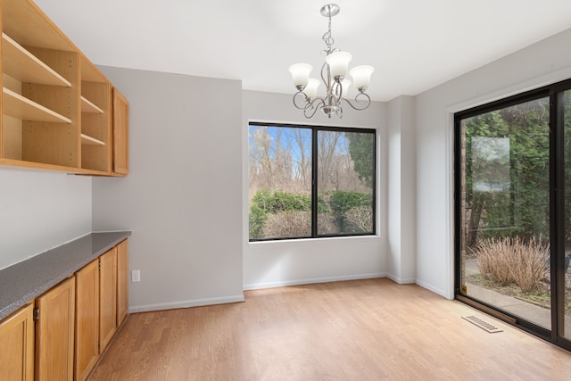 unfurnished dining area with light wood finished floors, a chandelier, and baseboards