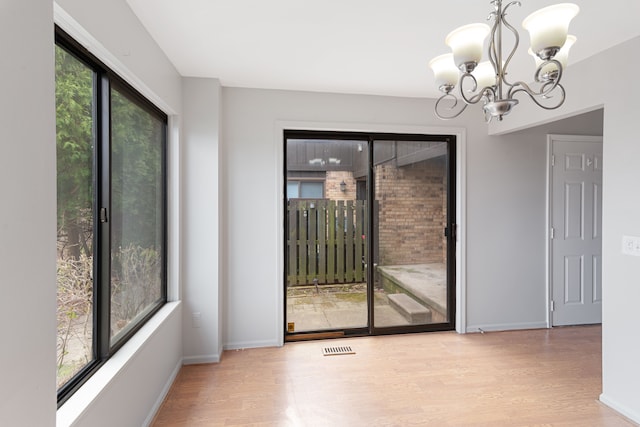 unfurnished dining area featuring a chandelier, wood finished floors, and baseboards