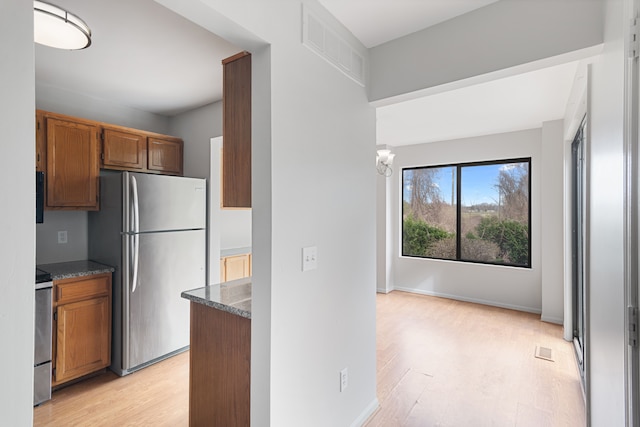 kitchen featuring freestanding refrigerator, brown cabinets, light wood finished floors, and range