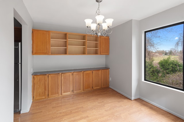unfurnished dining area featuring light wood finished floors, healthy amount of natural light, and a chandelier