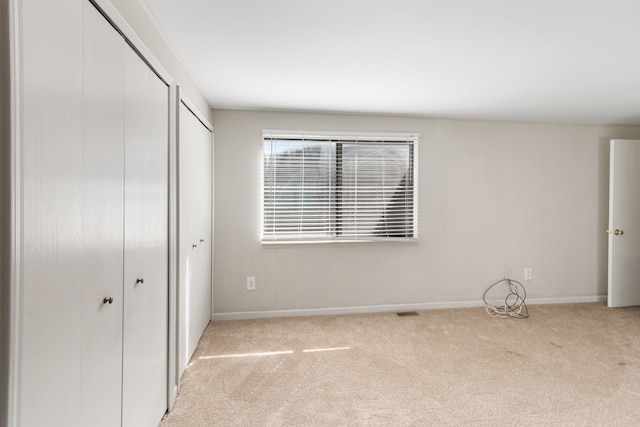 unfurnished bedroom with carpet flooring, baseboards, and multiple closets