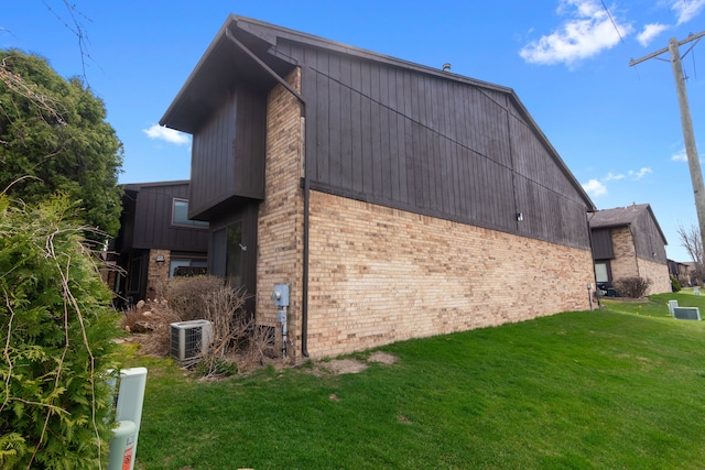 view of property exterior featuring brick siding, a yard, and central AC