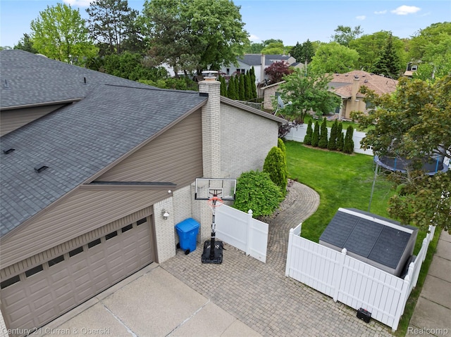 26155 Timber Trl, Dearborn Heights, MI 48127 - view of property exterior featuring a chimney, a garage, a shingled roof, a trampoline, and driveway