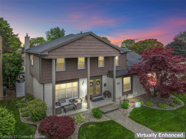 26155 Timber Trl, Dearborn Heights, MI 48127 - back of property at dusk featuring a chimney, brick siding, french doors, outdoor lounge area, and a patio area