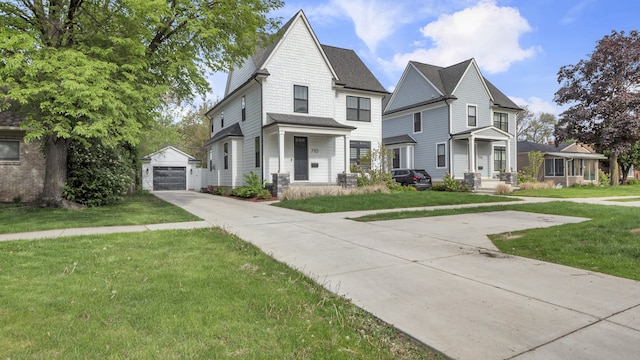 view of front of property featuring an outbuilding, concrete driveway, a front yard, and a detached garage