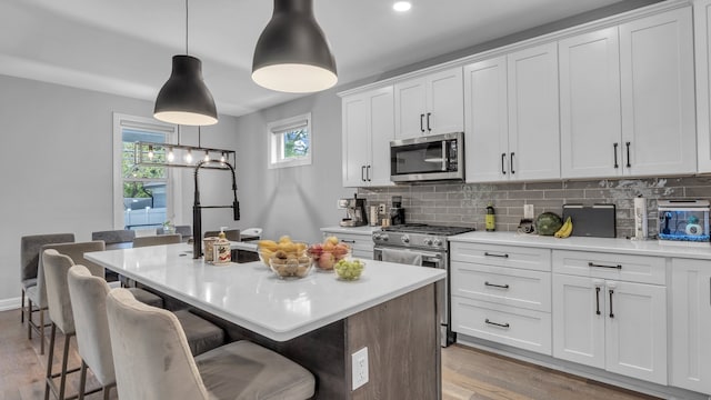 kitchen with appliances with stainless steel finishes, tasteful backsplash, light countertops, and recessed lighting