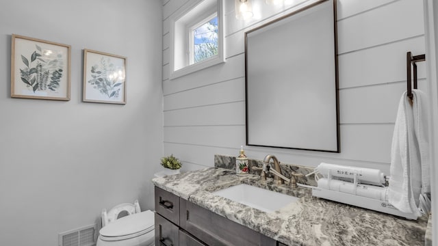half bathroom featuring vanity and toilet
