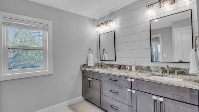 full bath featuring baseboards and double vanity