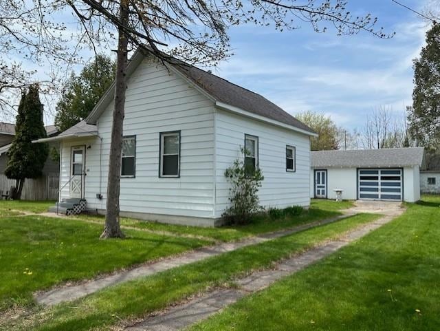 205 Evans St, East Tawas, MI 48730 - view of side of property featuring entry steps, a lawn, driveway, and an outbuilding