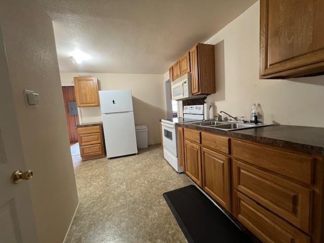 205 Evans St, East Tawas, MI 48730 - kitchen with white appliances, a sink, dark countertops, and brown cabinets
