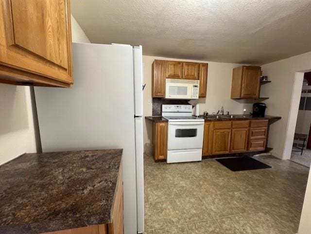 205 Evans St, East Tawas, MI 48730 - kitchen with white appliances, dark countertops, brown cabinetry, a sink, and a textured ceiling