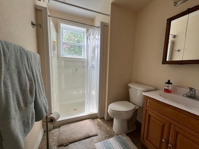 205 Evans St, East Tawas, MI 48730 - full bath featuring vanity, a shower stall, toilet, and tile patterned floors