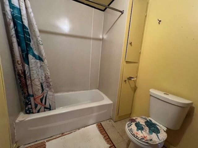 205 Evans St, East Tawas, MI 48730 - bathroom featuring shower / bathtub combination with curtain, tile patterned floors, and toilet