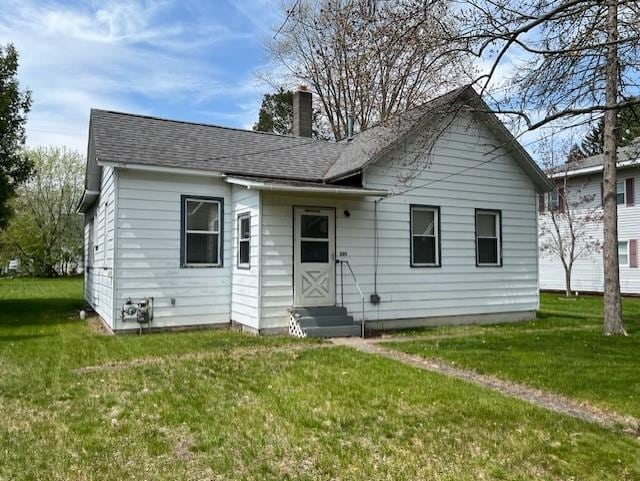 205 Evans St, East Tawas, MI 48730 - rear view of property with entry steps, a chimney, a lawn, and a shingled roof