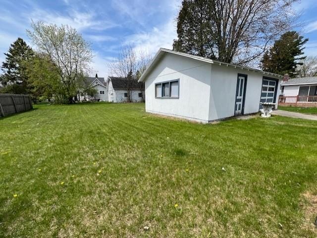 205 Evans St, East Tawas, MI 48730 - view of side of home with stucco siding and a lawn