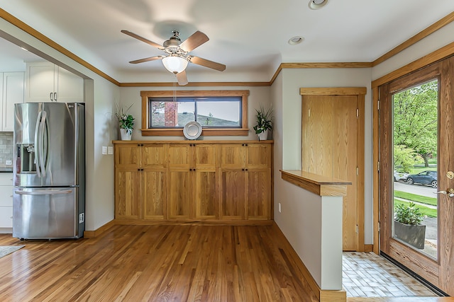 2441 Nottingham Rd, Ann Arbor, MI 48104 - kitchen featuring stainless steel fridge, white cabinets, ceiling fan, baseboards, and crown molding