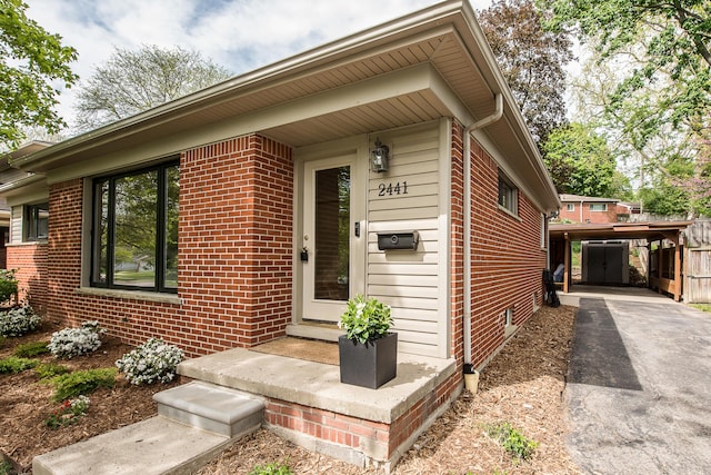 2441 Nottingham Rd, Ann Arbor, MI 48104 - doorway to property with brick siding, a carport, and asphalt driveway