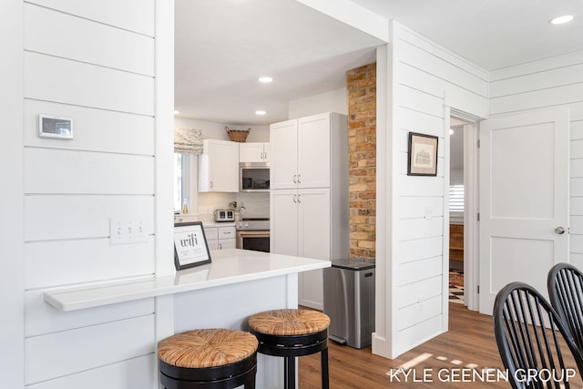 2245 Auburn Ave, Holland, MI 49424 - kitchen with stainless steel appliances, a breakfast bar, wood finished floors, white cabinets, and light countertops
