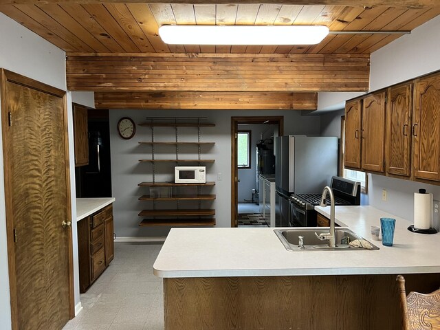 8711 M-37, Irons, MI 49644 - kitchen with wood ceiling, white microwave, a peninsula, light countertops, and freestanding refrigerator