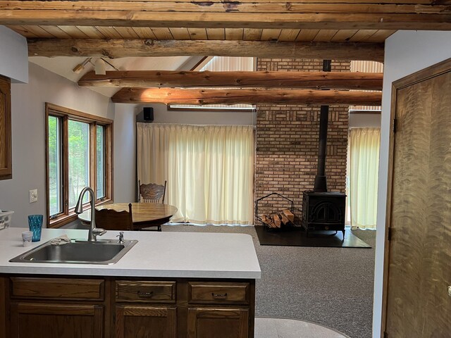 8711 M-37, Irons, MI 49644 - kitchen featuring a sink, wood ceiling, beam ceiling, a wood stove, and light countertops