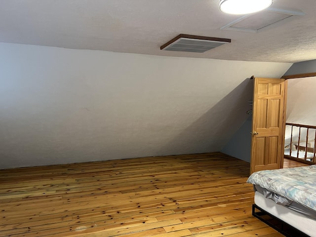 8711 M-37, Irons, MI 49644 - bedroom featuring lofted ceiling, wood-type flooring, and attic access