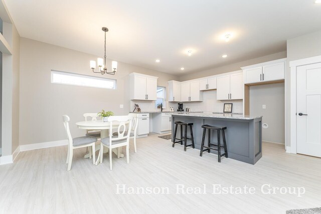 1422 Center Hill Rd SE Unit 46, Lowell, MI 49331 - kitchen featuring a kitchen island, a chandelier, white cabinets, backsplash, and light wood-style flooring