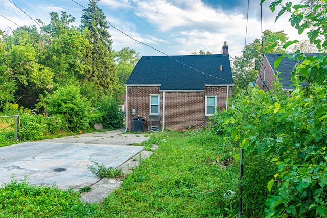 15596 Eastwood St, Detroit, MI 48205 - rear view of house featuring brick siding, a chimney, roof with shingles, and a patio