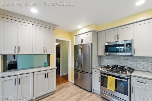 6605 Northview Dr, Clarkston, MI 48346 - kitchen featuring appliances with stainless steel finishes, light wood-style floors, backsplash, light stone countertops, and recessed lighting