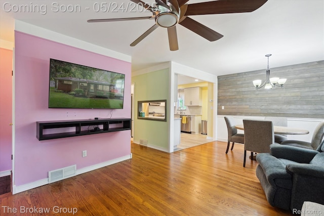 6605 Northview Dr, Clarkston, MI 48346 - living area with a chandelier, wood finished floors, ceiling fan, baseboards, and wood walls