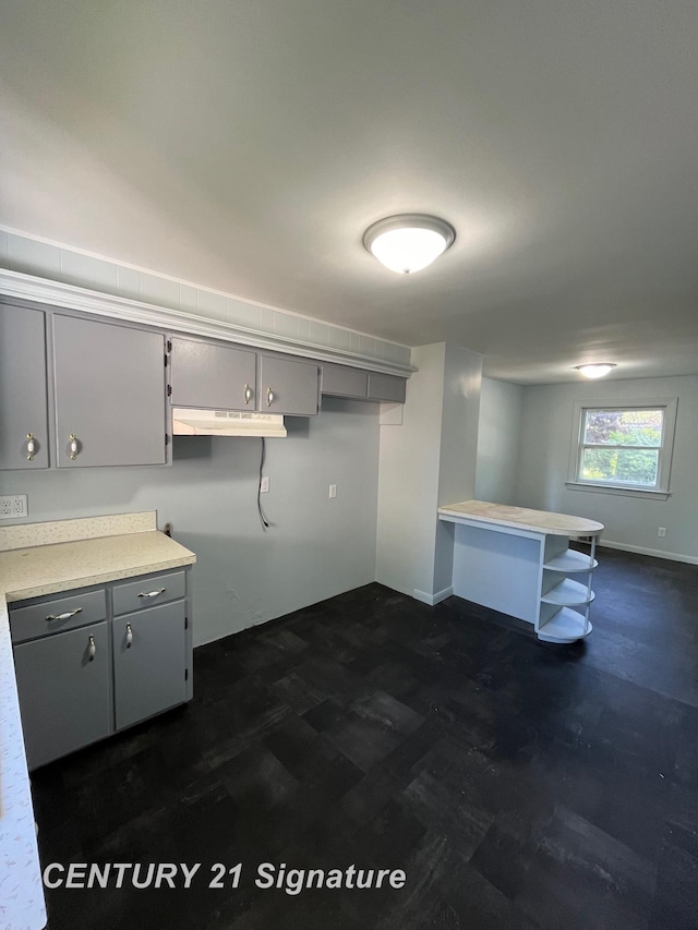 2222 Stone St, Saginaw, MI 48602 - kitchen with gray cabinets, under cabinet range hood, a peninsula, light countertops, and baseboards