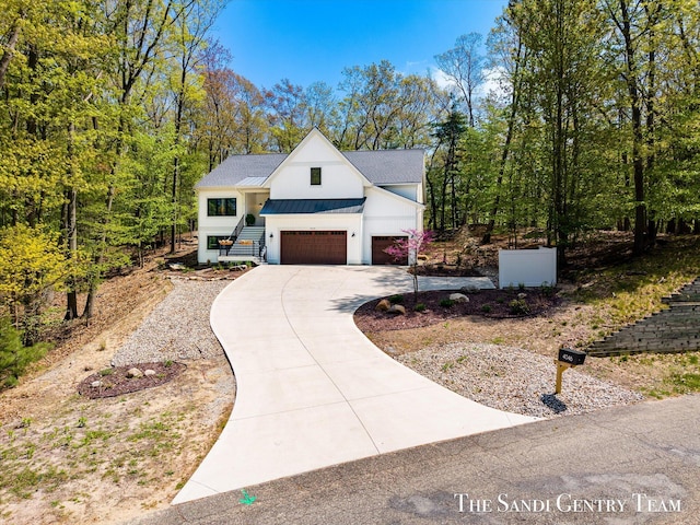 view of side of property featuring concrete driveway, a standing seam roof, board and batten siding, metal roof, and an attached garage