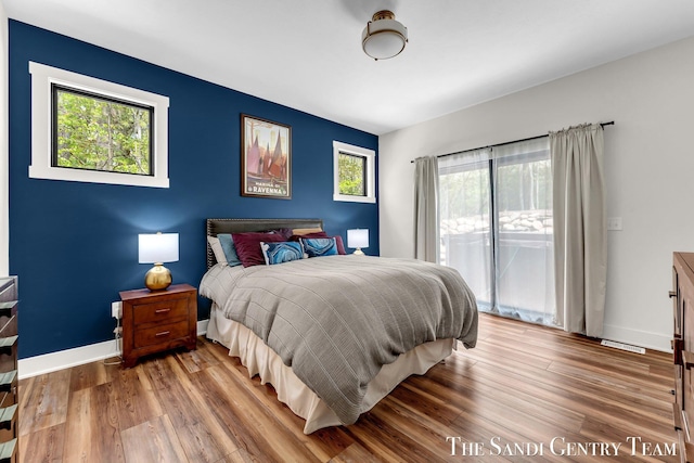 bedroom featuring access to exterior, wood finished floors, and baseboards