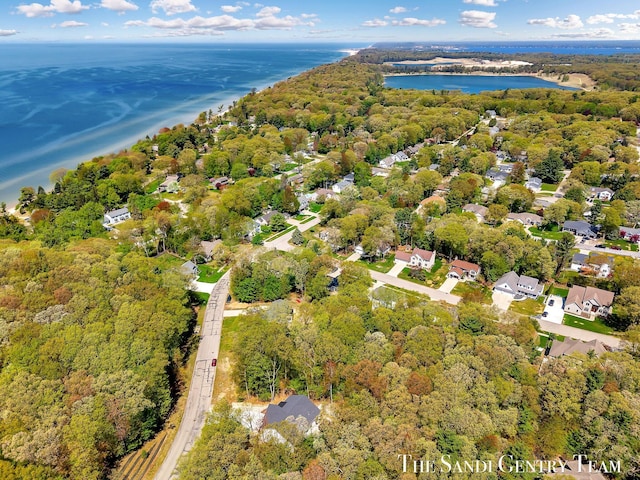 aerial view of property and surrounding area with a nearby body of water and a heavily wooded area