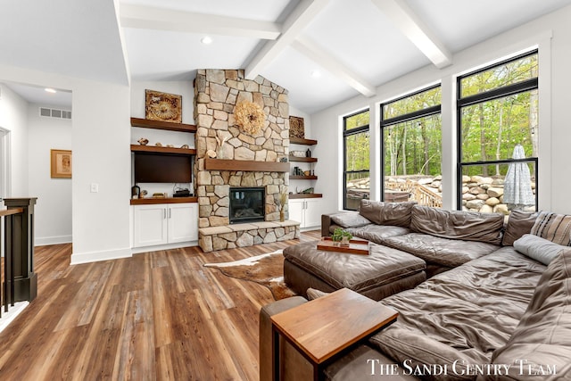 living area featuring wood finished floors, a stone fireplace, and baseboards