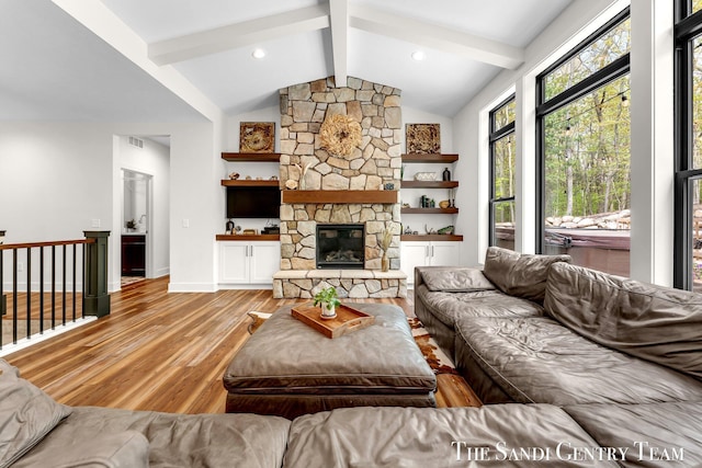 living room with wood finished floors and a stone fireplace