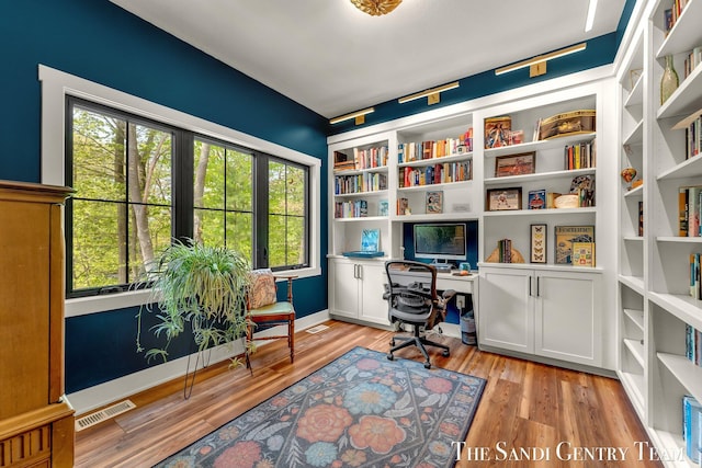 office space featuring healthy amount of natural light, built in study area, light wood finished floors, and baseboards