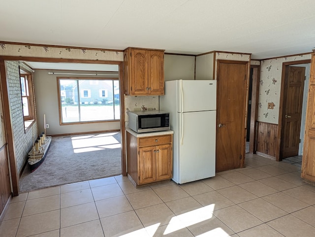 602 Fourth St, Ludington, MI 49431 - kitchen featuring freestanding refrigerator, stainless steel microwave, brown cabinetry, light colored carpet, and light countertops