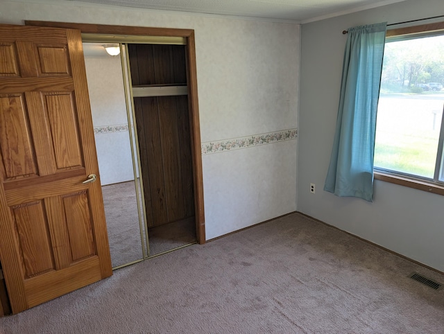 602 Fourth St, Ludington, MI 49431 - unfurnished bedroom with light carpet, ornamental molding, and a closet