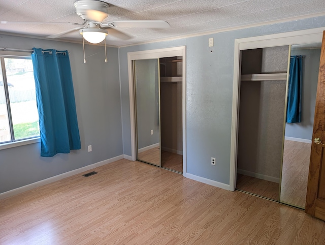 602 Fourth St, Ludington, MI 49431 - unfurnished bedroom with light wood-style floors, two closets, a ceiling fan, and baseboards