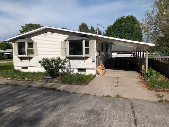 602 Fourth St, Ludington, MI 49431 - manufactured / mobile home with concrete driveway, a carport, and fence