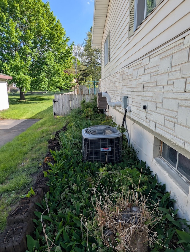 602 Fourth St, Ludington, MI 49431 - exterior view of fence, central AC unit, and stone siding