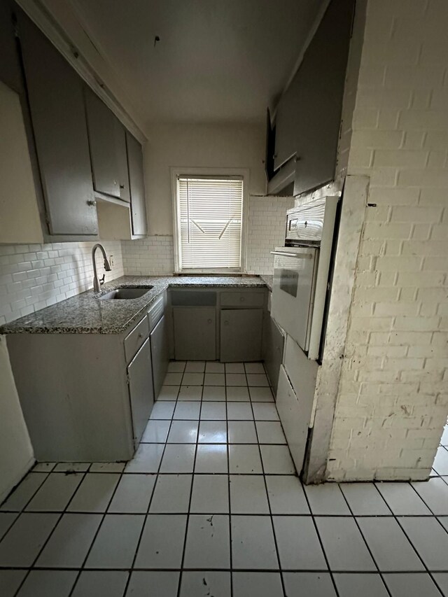19731 Harlow St, Detroit, MI 48235 - kitchen featuring oven, a sink, backsplash, light stone countertops, and light tile patterned flooring
