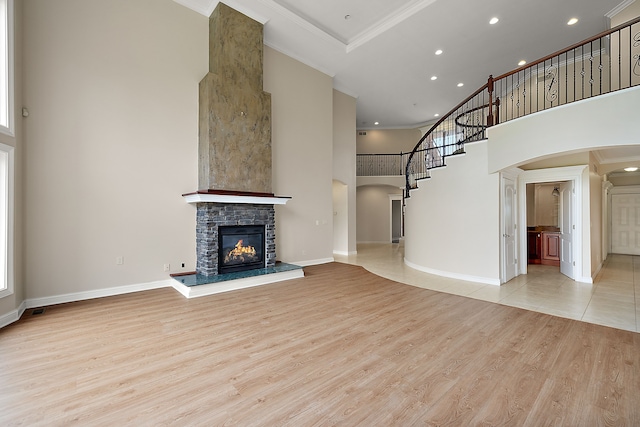 66701 Notre Dame Blvd, Washington, MI 48095 - unfurnished living room with arched walkways, a towering ceiling, crown molding, light wood-type flooring, and a stone fireplace